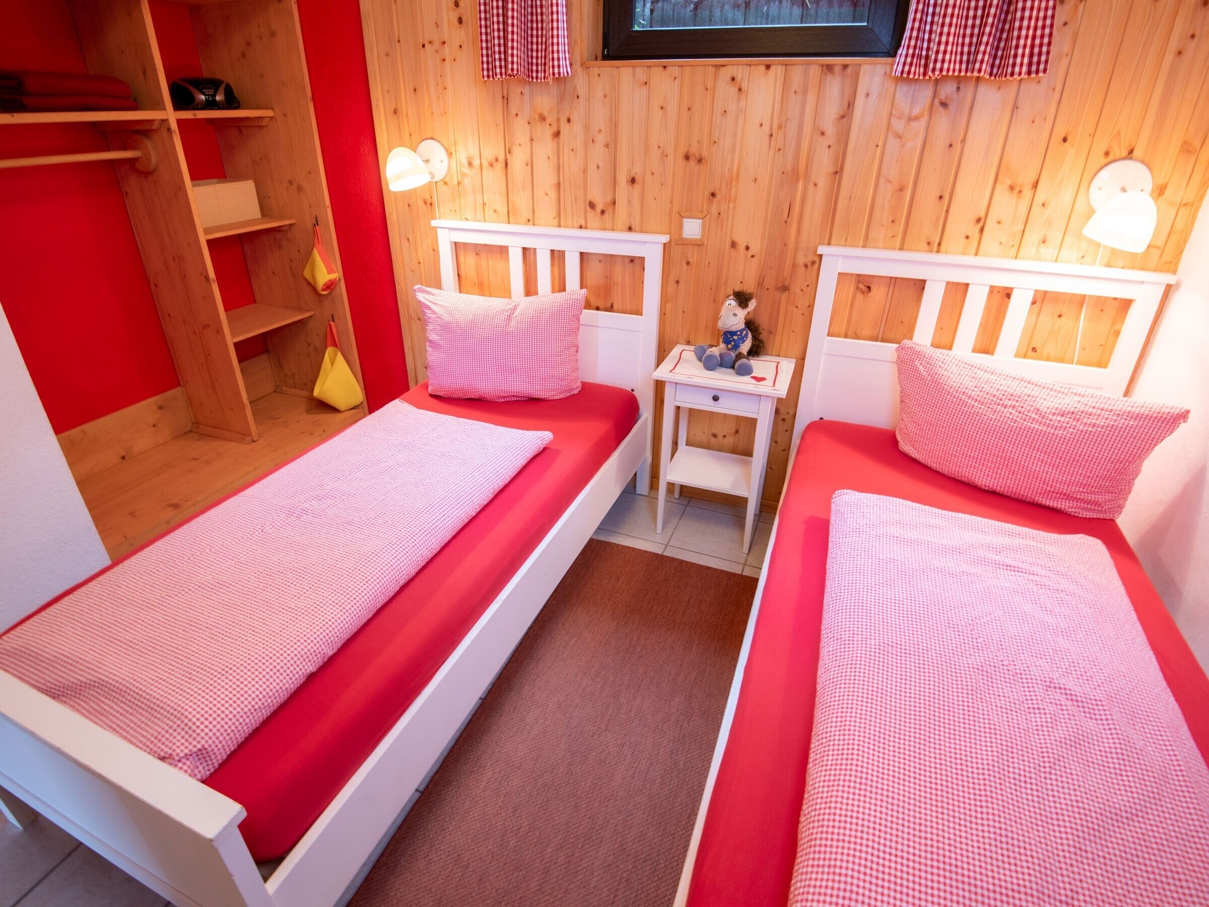 Ein Zimmer mit zwei Betten, Holzwänden, einem kleinen Tisch und einem Fernseher.