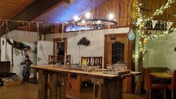 A rustic wooden interior with a central wooden table, chairs, and a chandelier.