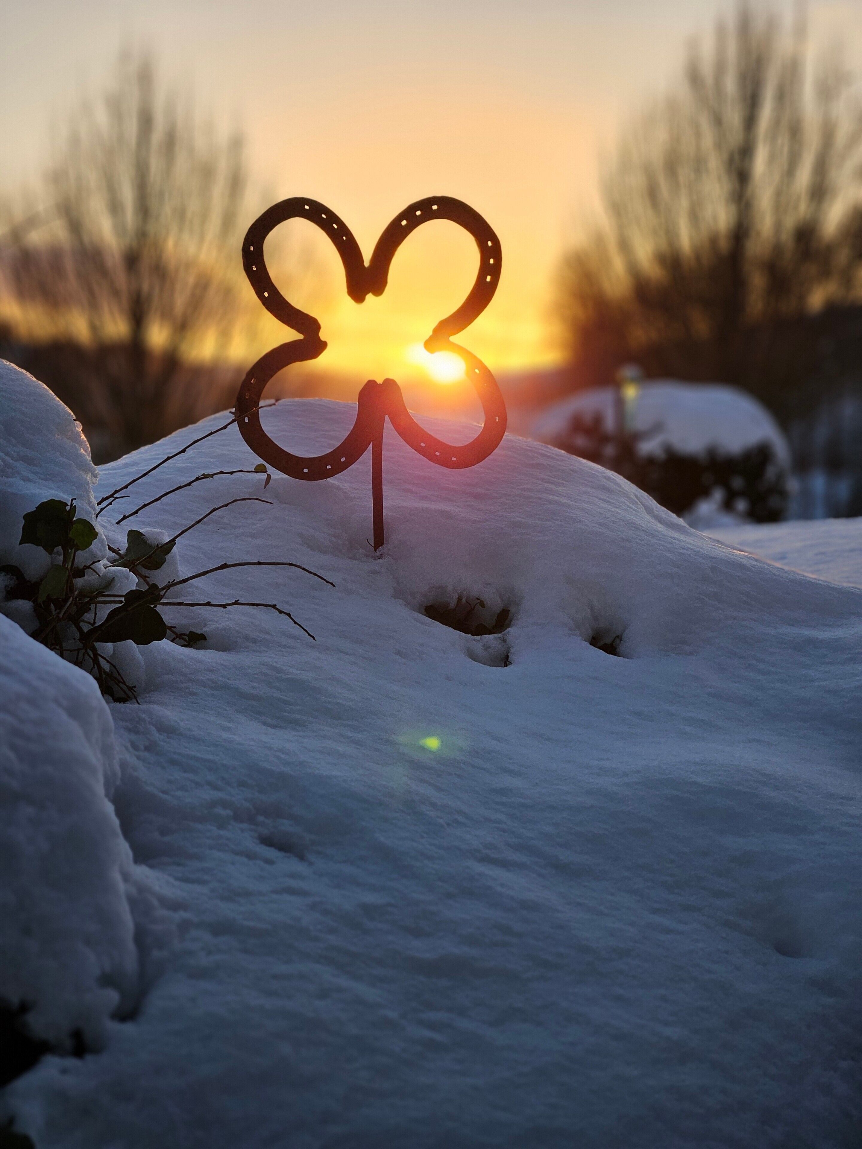 A snow-covered landscape with a heart-shaped decoration in the foreground.