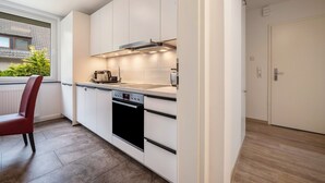 Una cocina moderna con armarios blancos, horno empotrado y ventana con vistas a zonas verdes.