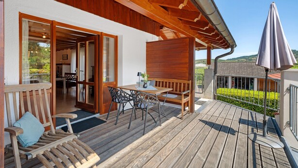 A wooden deck with outdoor furniture, a table, and a bench. - Apartment '2, 65 Qm, Balkon' with Shared Pool, Private Terrace and Wi-Fi (Vogtsburg)