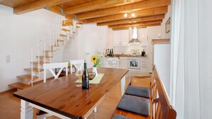 A modern kitchen with white cabinets, a wooden dining table, and a staircase leading to an upper level. - Apartment '2, 65 Qm, Balkon' with Shared Pool, Private Terrace and Wi-Fi (Vogtsburg)