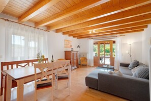 A wooden ceiling, a dining table with chairs, a sofa, and a cabinet.