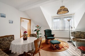 Uma sala de jantar com mesa, cadeiras, uma planta e um sofá.