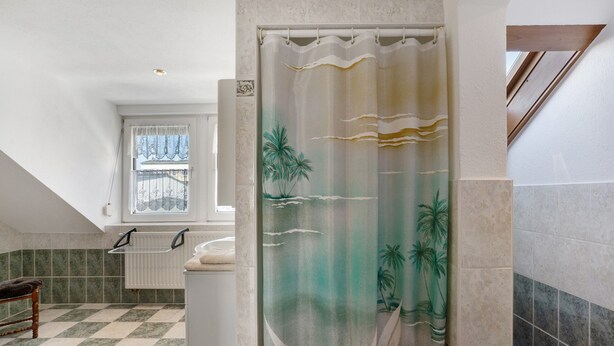 A bathroom with a shower curtain depicting palm trees and waves, a window with a view, a radiator, and a checkered floor. - Apartment 'Annemarie Galle' with Wi-Fi (Meißen)