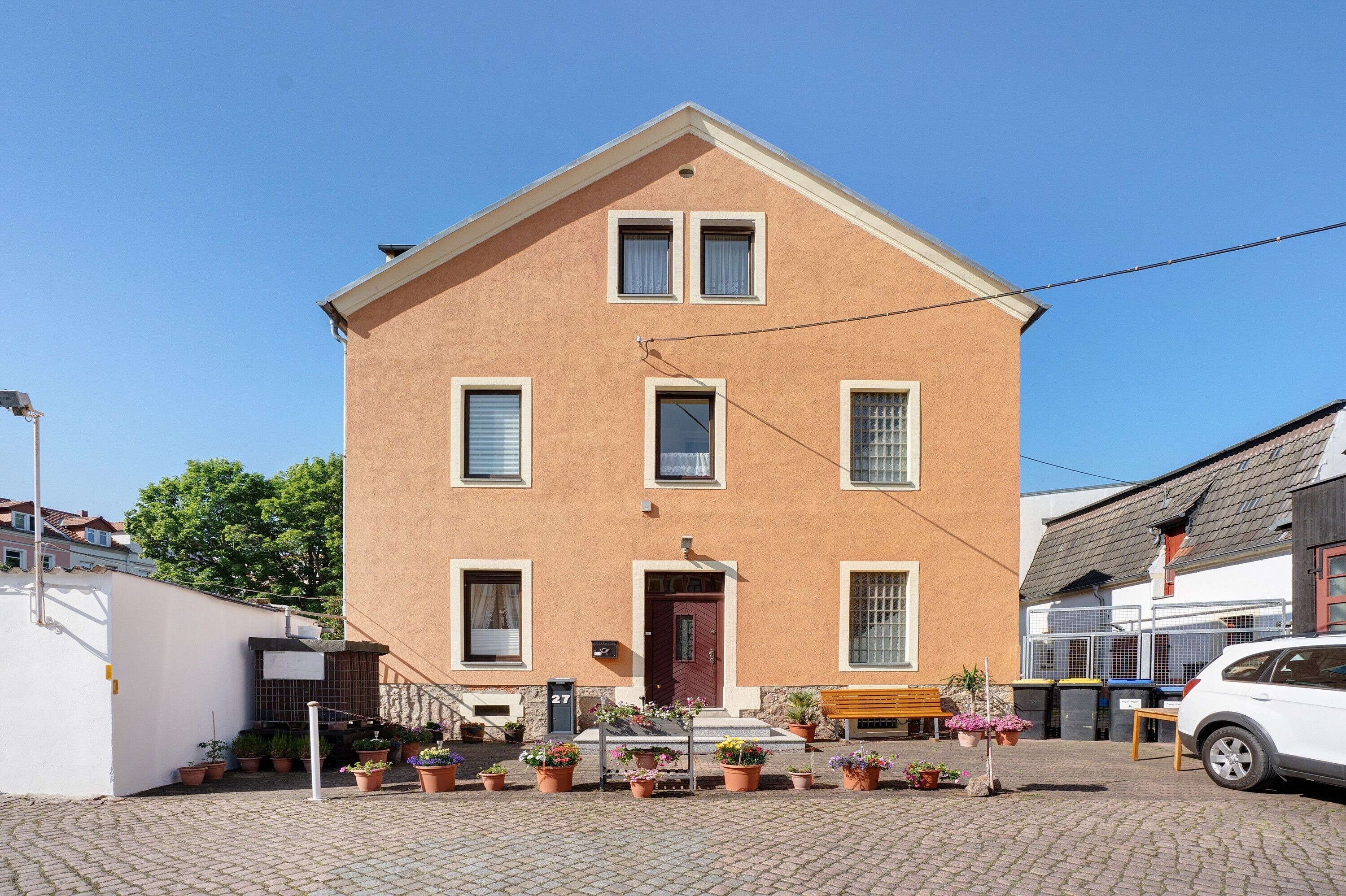 Ein zweistöckiges Gebäude mit einer braunen Fassade, einer Haustür und mehreren Fenstern.