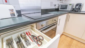 Eine Küche mit Mikrowelle, Toaster und einer Schublade voller Küchenutensilien.