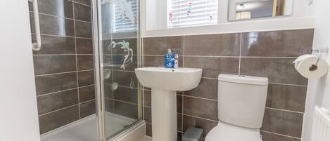 A bathroom with a glass shower enclosure, a pedestal sink, and a toilet.