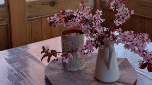 Un interior de madera con una mesa que presenta un jarrón de flores rosas, una cesta decorativa y un pequeño candelabro.