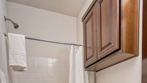 A bathroom with a bathtub, toilet, and wooden cabinets.