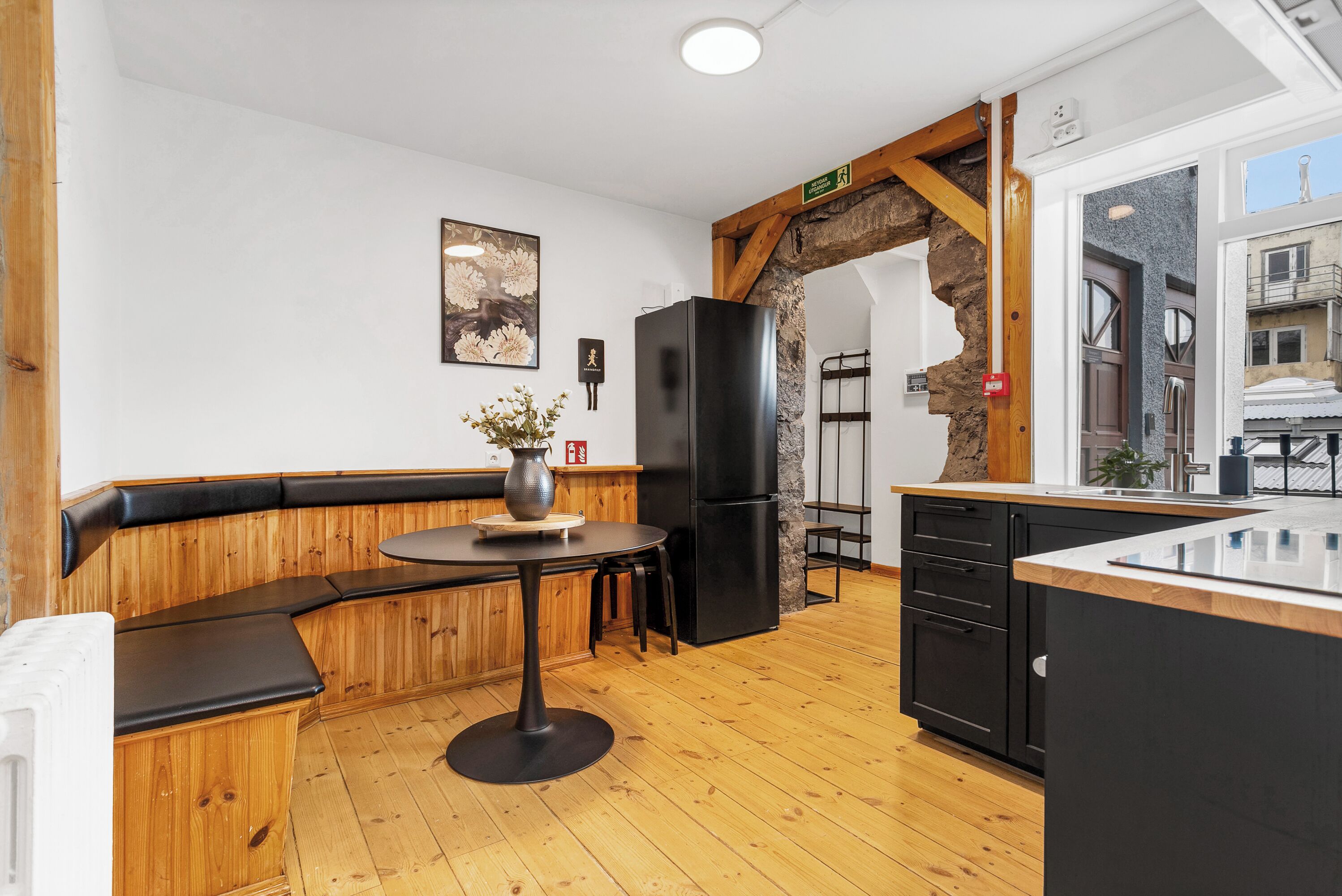 A modern kitchen with wooden accents, a black refrigerator, and a stone archway.