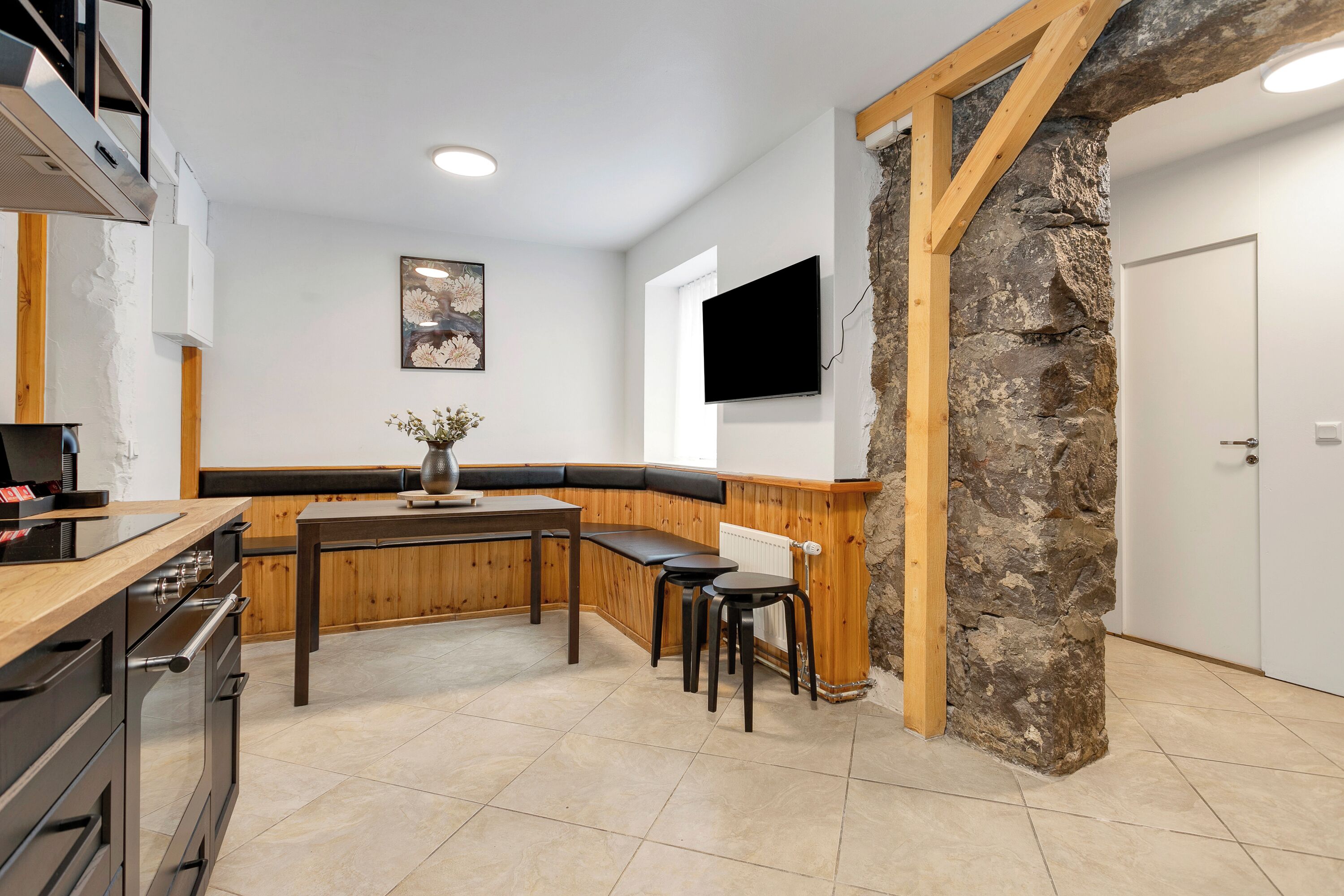 Una cocina moderna con un banco de madera, una pared de acento de piedra y un televisor de pantalla plana.