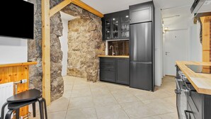 Une cuisine moderne avec un mur d’accent en pierre, des armoires noires et un comptoir en bois.
