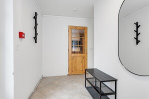 A hallway with a wooden door, a black bench, and a wall-mounted circular mirror.