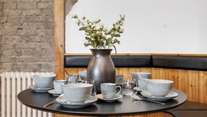 Une table ronde avec une carafe et un service à thé, placée devant un mur de briques et un lambris en bois.