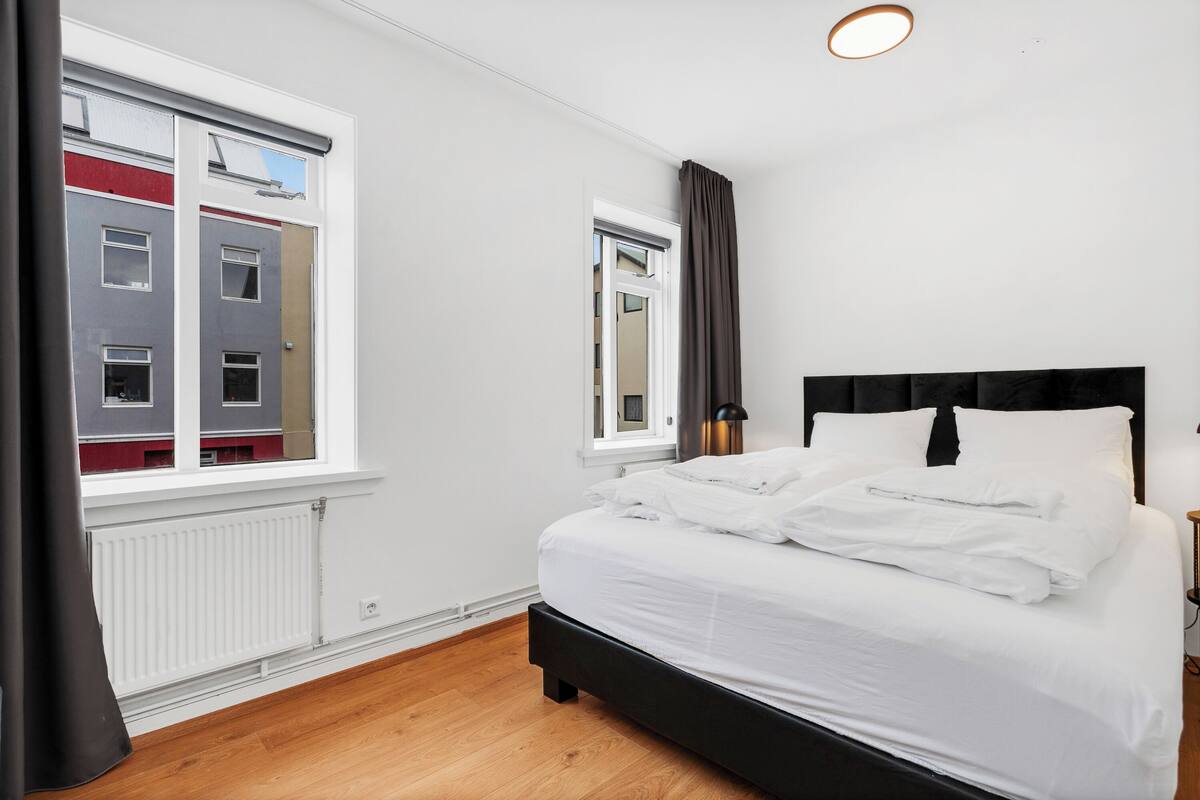 Un dormitorio con cama, ventana, radiador y puerta.