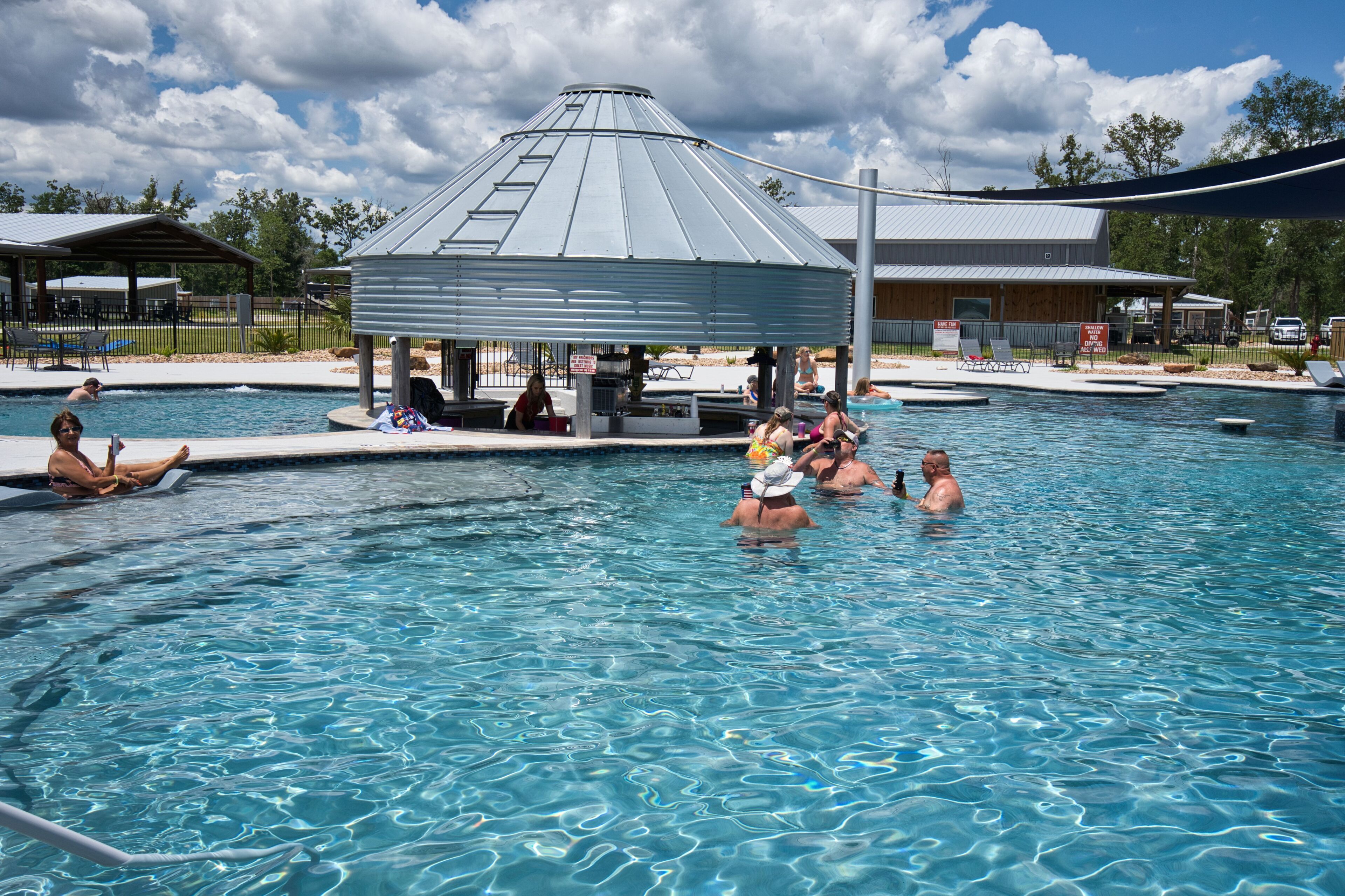A swimming pool with a gazebo, lounge chairs, and a covered area.