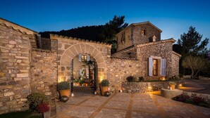 A stone building with an arched entrance, potted plants, and a stone pathway.