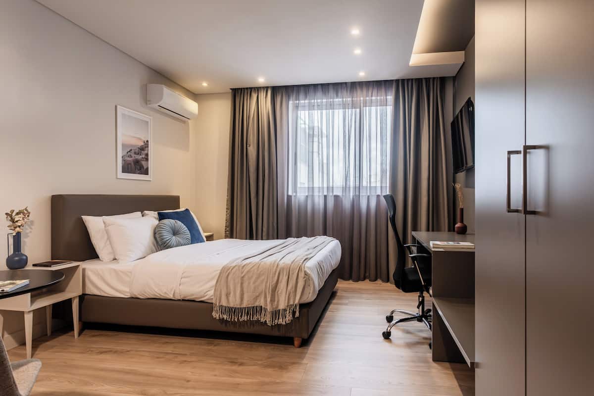 A modern bedroom with a large bed, a desk, and a chair.