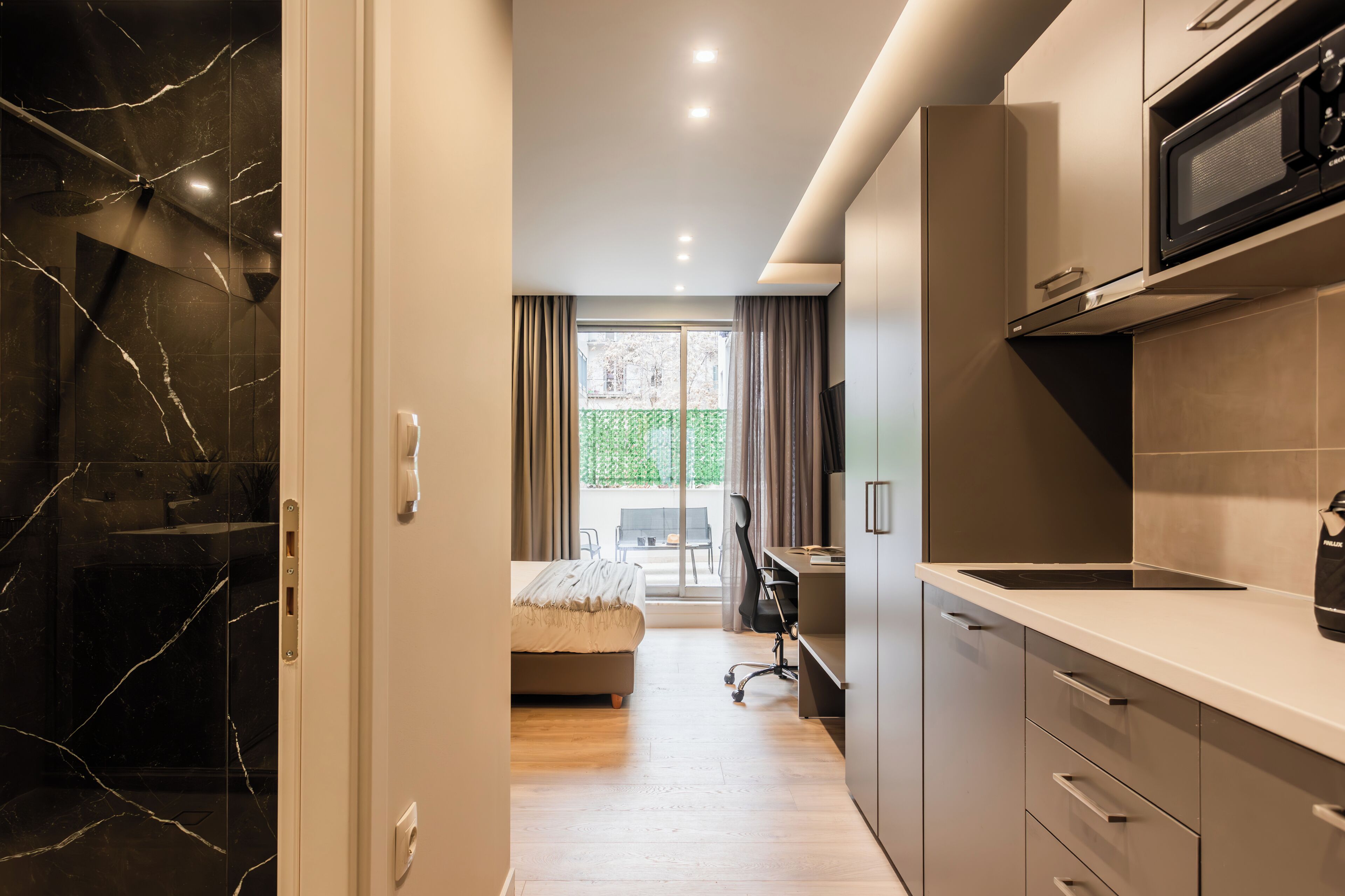 A modern kitchen with a microwave, a sink, and a dining area with a table and chairs.