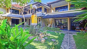 A two-story building with a covered patio area, a statue, and a stone pathway. - Anna Kuta Inn Hotel (Kuta)