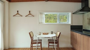 A kitchen with a window, wooden chairs, a table, and a hanging light fixture. - Boeun Pension at 77 Igashinjeong-gil (Boeun)