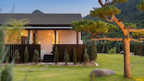 A modern house with a wooden deck, a stone pathway, and a well-maintained lawn. - Boeun Pension at 77 Igashinjeong-gil (Boeun)