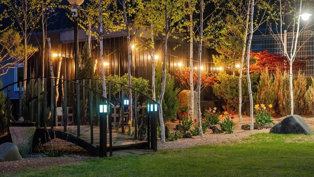 A garden with a wooden bridge, trees, and a building in the background. - Boeun Pension at 77 Igashinjeong-gil (Boeun)