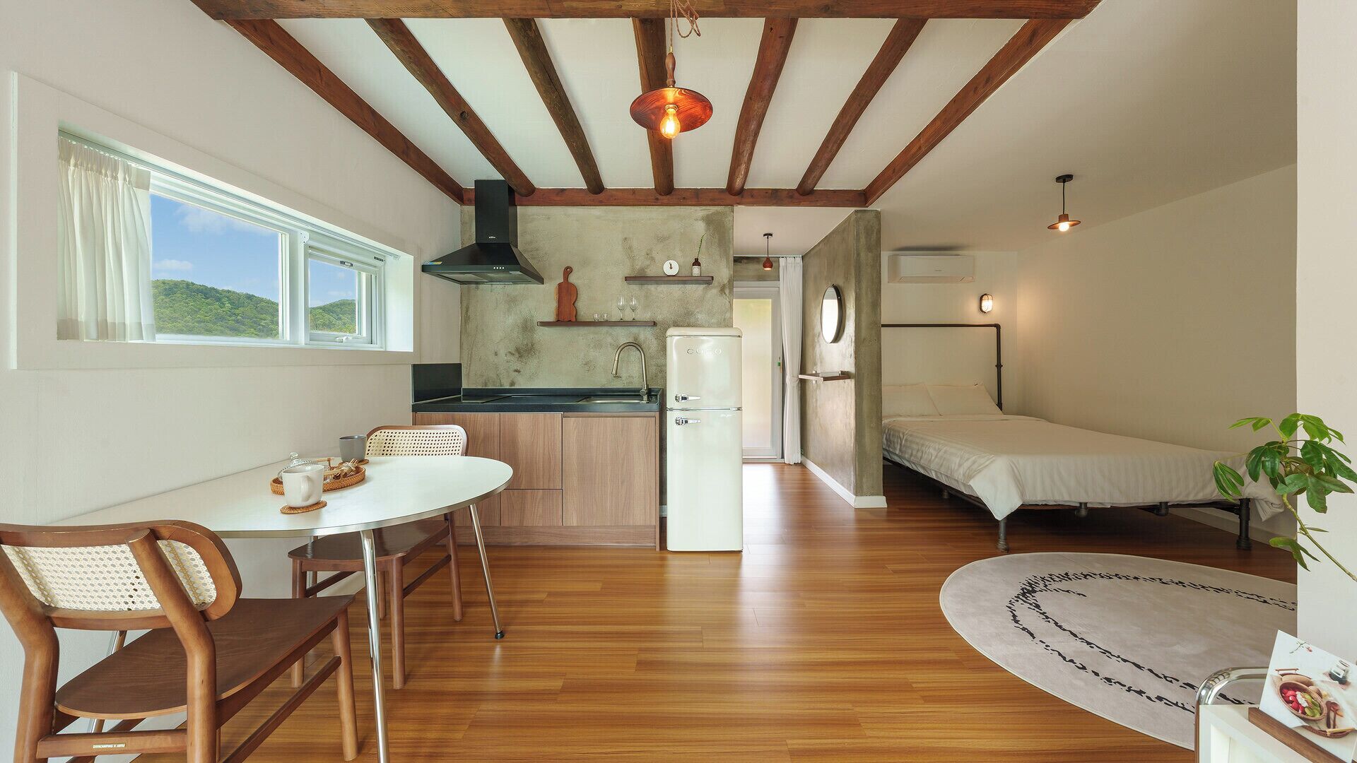 A compact kitchen with a dining area, a bed, and a view of the outdoors.