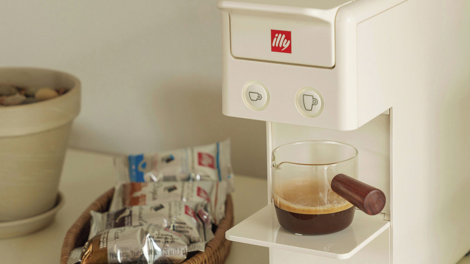 Eine Kaffeemaschine mit einer Tasse Kaffee, einer Kaffeepad-Box und einer Schüssel.