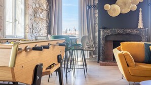 A room with a pool table, a fireplace, and a view of a cityscape.