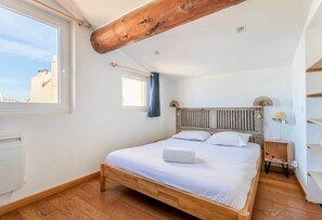 Une chambre à coucher avec un lit en bois, une fenêtre et une vue sur des immeubles.