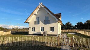 Une maison à deux étages avec un toit à pignon, un petit porche à l’avant et une cour clôturée.