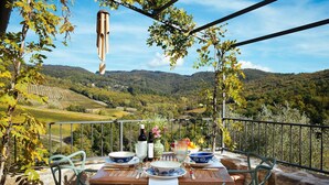 A table set outdoors with a view of vineyards and hills. - My Rental Homes - Villa Torre del Chianti with hited pool, Gym and wellness center (Radda In Chianti)