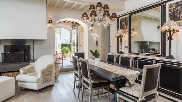 A dining area with a large table, chairs, and a chandelier. There is a fireplace and a large mirror on the wall. - My Rental Homes - Villa Chianti with private pool, SPA and Gym (Tavarnelle Val Di Pesa)