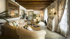 A cozy, well-lit room with wicker furniture, a dining table set with a tray, and a large mirror on the wall. - My Rental Homes - Villa Chianti with private pool, SPA and Gym (Tavarnelle Val Di Pesa)