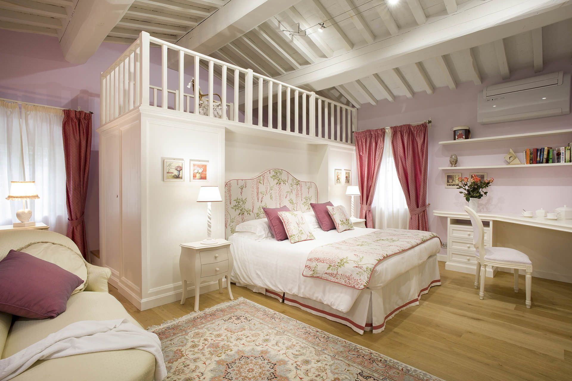 Ein Schlafzimmer mit einem Schlafplatz auf Hochbett, einem Schreibtisch und einem Stuhl.