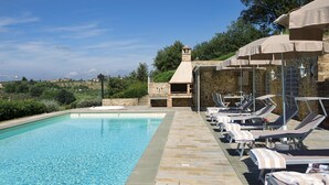 A swimming pool with lounge chairs and a stone building with a chimney. - My Rental Homes - Villa Chianti with private pool, SPA and Gym (Tavarnelle Val Di Pesa)