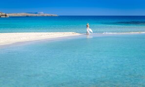 Une plage à l’eau turquoise et limpide, bordée d’un rivage sablonneux.