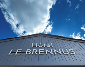 A hotel sign with the name "Hotel Le Brennus" against a clear blue sky with clouds. - Hotel Restaurant Le Brennus (Logis Hotel) (Langon)
