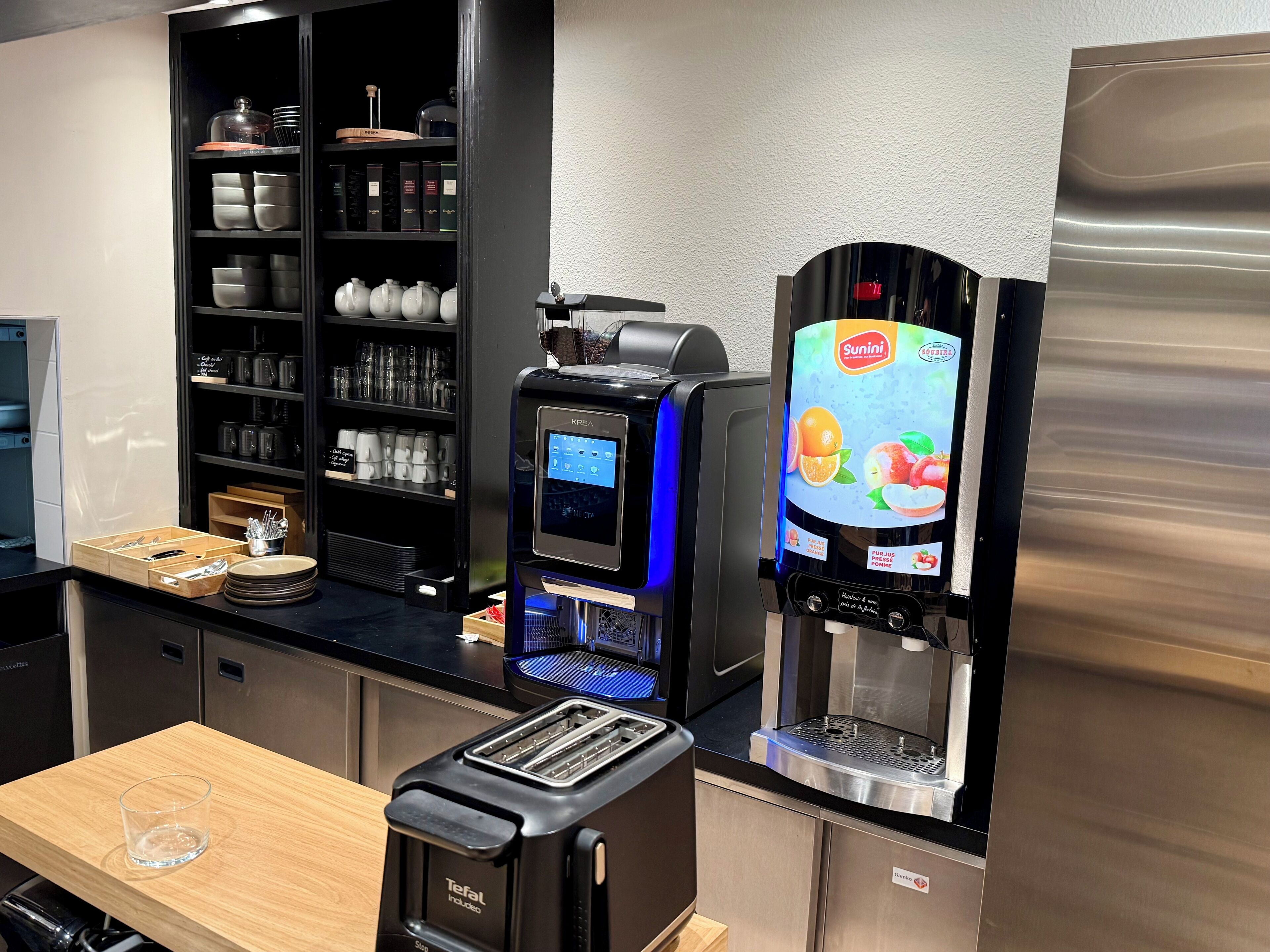 A modern kitchen with a coffee machine, a toaster, and a refrigerator.