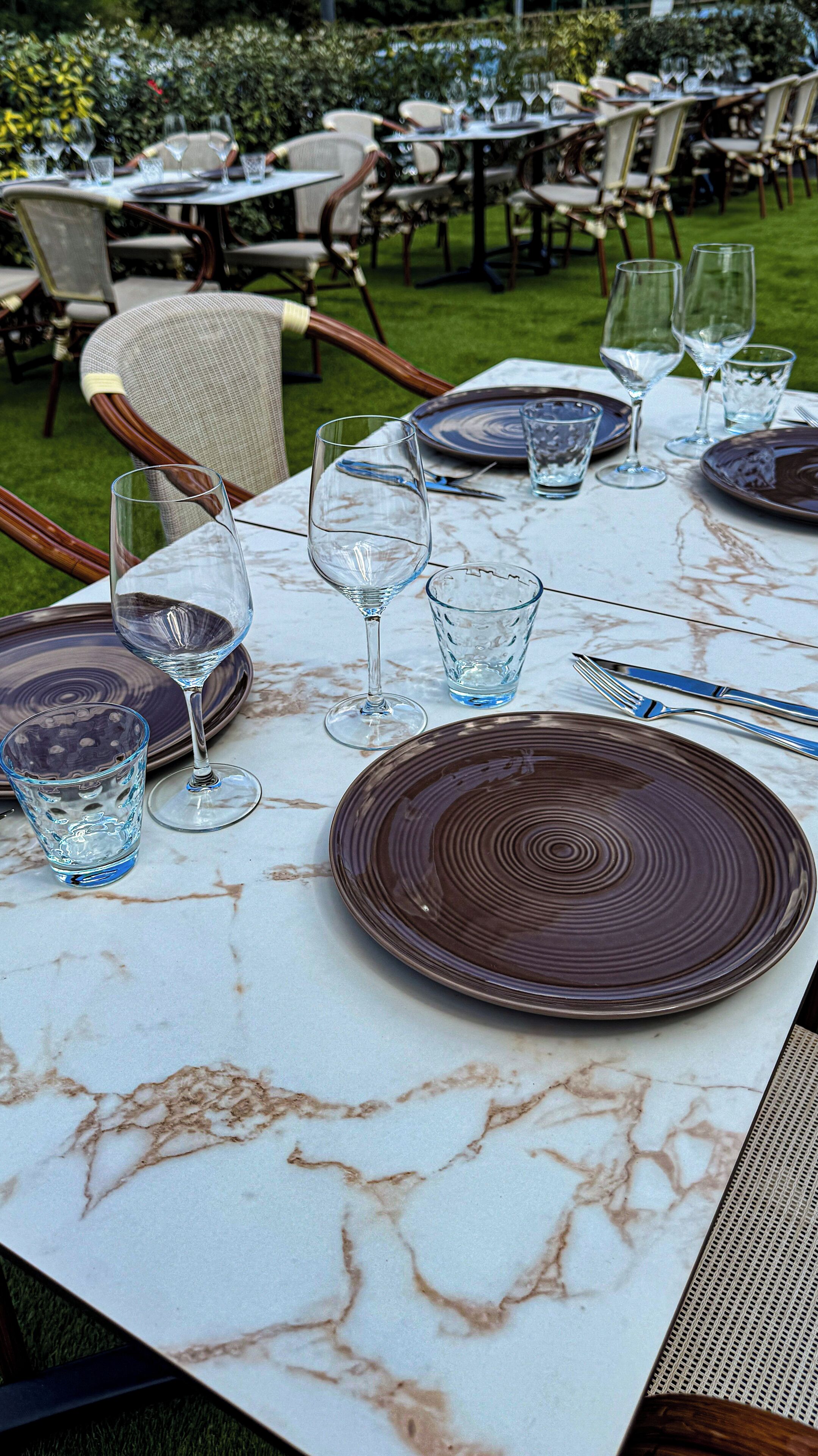 Ein Tisch im Freien mit Tellern, Gläsern und Besteck.