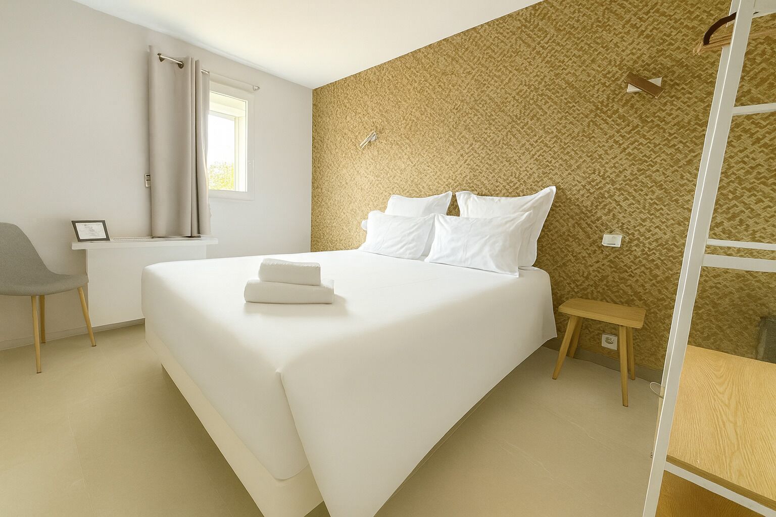 A modern hotel room with a large bed, a desk, and a chair.