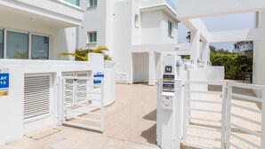 A modern building with white exterior walls, multiple balconies, and a gated entrance. - Green Bay Villa #14 (Paralimni)