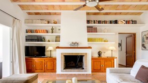 Un salon avec une cheminée, des étagères à livres, un téléviseur et un canapé.
