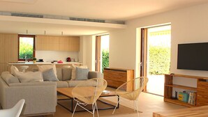 A modern living room with a sofa, two wicker chairs, a coffee table, and a TV on a wooden stand. - My Rental Homes - Villa Acapulco private pool, barbeque and wifi (Palma De Mallorca)