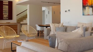 A modern living room with a sofa, two wicker chairs, a coffee table, and a dining area with a table and chairs. - My Rental Homes - Villa Acapulco private pool, barbeque and wifi (Palma De Mallorca)
