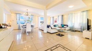 A spacious living area with a dining table, sofas, and a TV. - Royal Beachfront Villa (Paralimni)