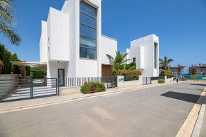 A modern building with a large window, a gated entrance, and a clear sky. - By The Beach - Sea Pearl Villa (Paralimni)