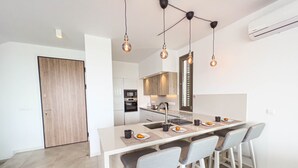 A modern kitchen with a central island, bar stools, and pendant lighting. - Azure Seaview - Jade Villa (Paralimni)